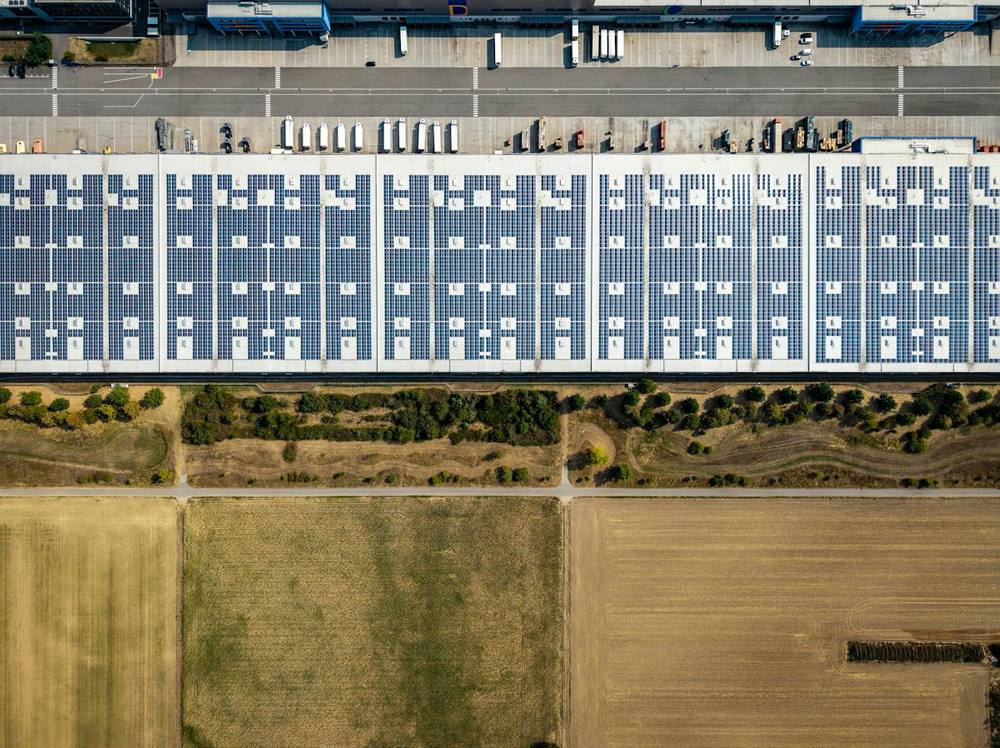 Vista aérea de galpão com telhado metálico coberto de placas solares
